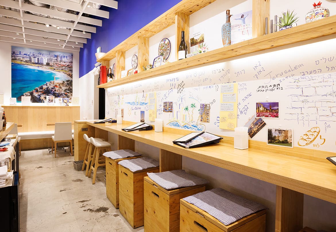カウンター席も広々。地中海を思わせるカラーと、ヘブライ文字の落書きがかわいい