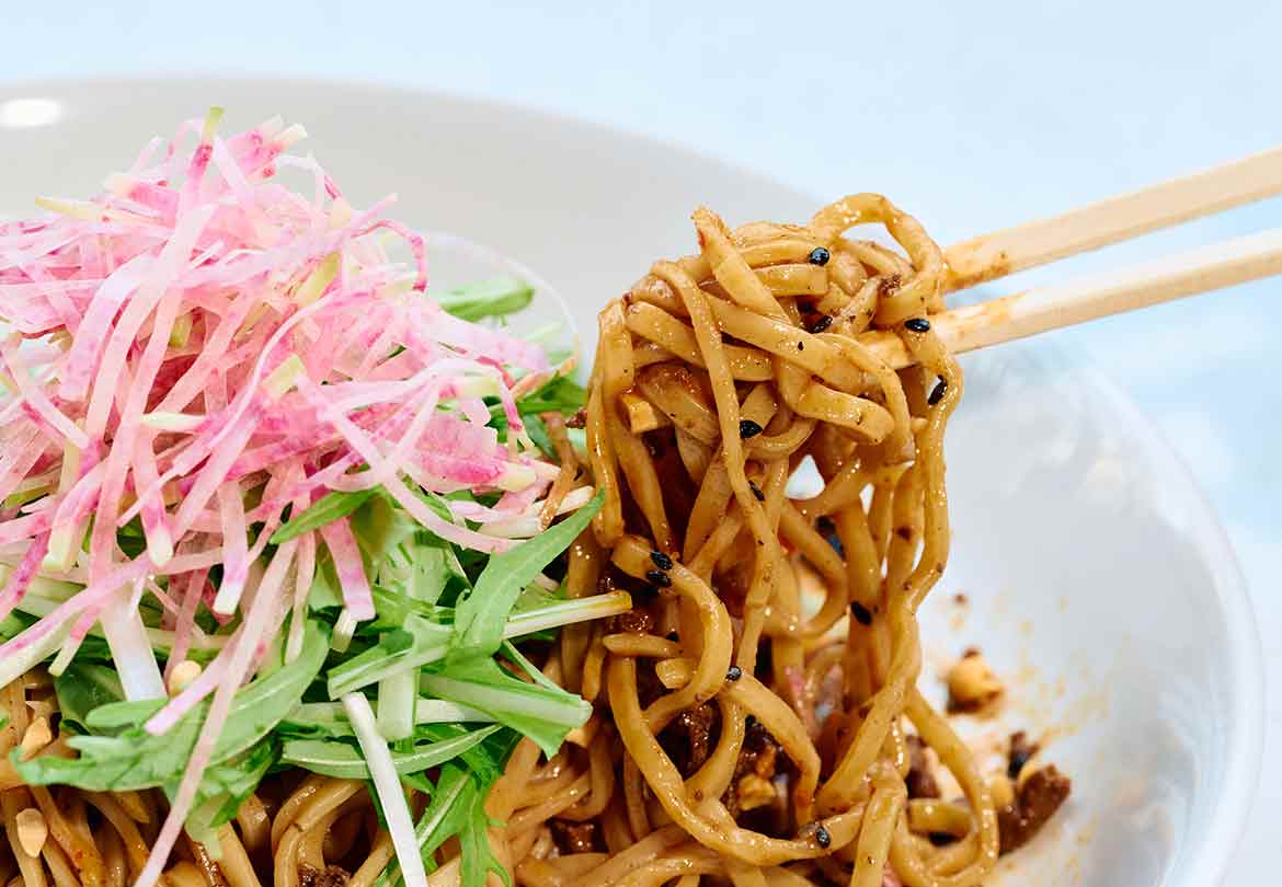 平たいたまご麺にタレがしっかり絡む