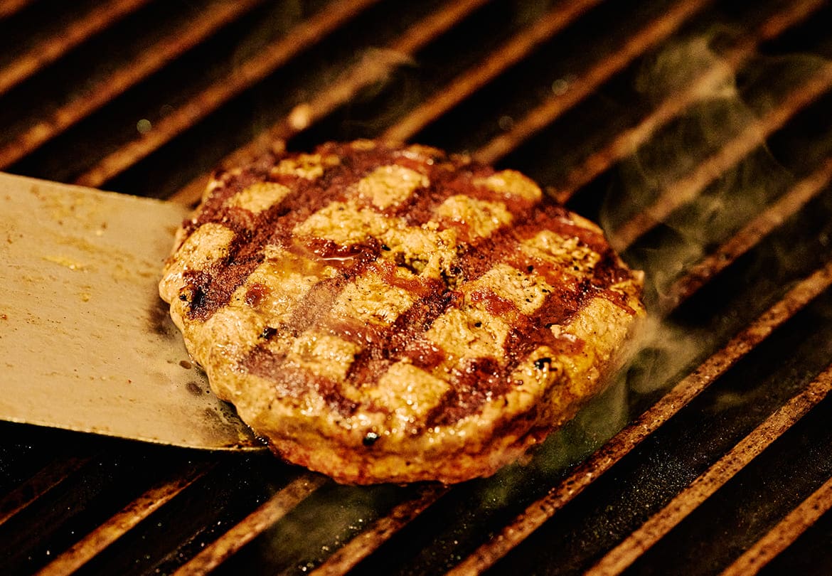 バーガーのパティはオージービーフ100％。余分な油を落としながら焼き上げる