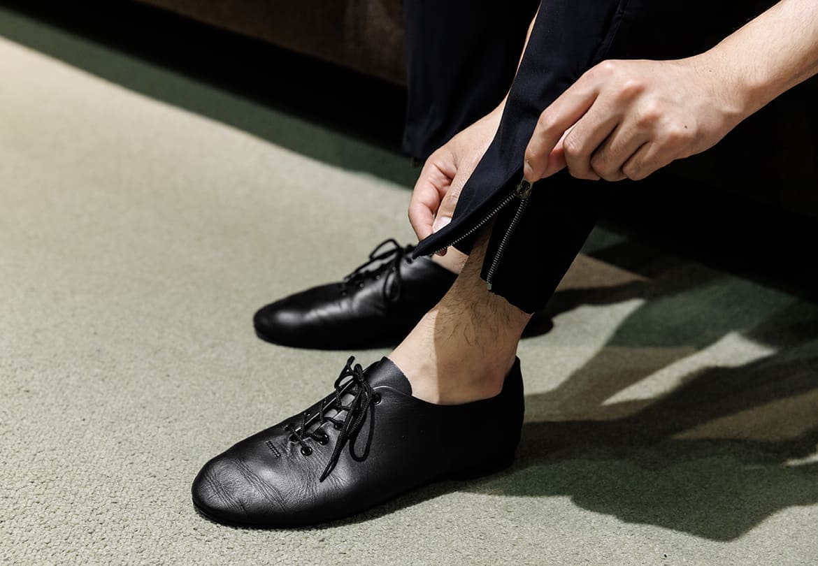 ストレッチが効いた素材のパンツは裾にジップ付き。足元をレザーにすればスポーティすぎない