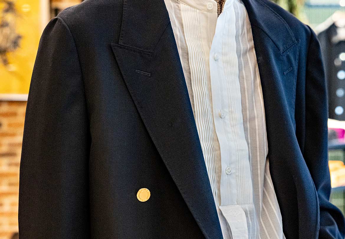 特徴的なノーカラーシャツをアクセントに