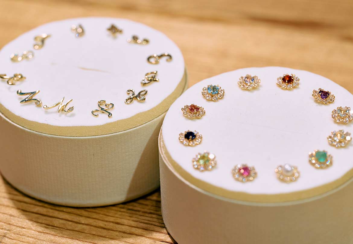 「イニシャル ダイヤモンド ピアス | K10YG 〈片耳〉」8,250円／「カラーストーン フラワー ピアス | K10YG 〈誕生石〉」14,300円